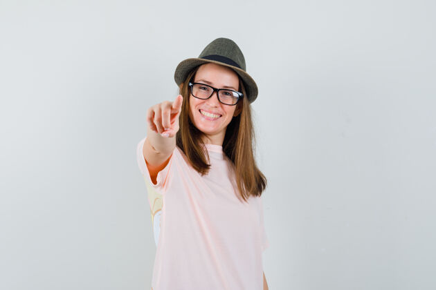 帽子一位戴着粉色t恤帽子的年轻女士指着镜头 看上去很快乐兴奋时尚积极