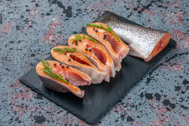 美食侧视图新鲜切割生鱼绿色深色托盘上蓝黑色混合颜色表与自由空间菜肴托盘肉
