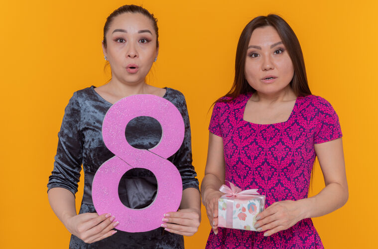 亚洲两位快乐又惊喜的亚洲女性在庆祝国际妇女节时举着8号女人礼物惊喜