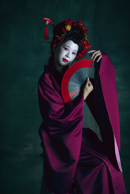 勇敢梦幻年轻的日本女人像艺妓一样孤立在深绿色的墙上复古的风格 比较时代的概念漂亮的女模特喜欢鲜明的历史人物 老式的贵族女人文艺复兴