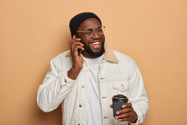 微笑黑皮肤的男人在电话里谈笑风生 在电话里谈笑风生说话请信息
