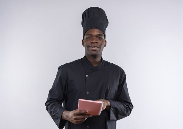 复制身着厨师制服的年轻美籍黑人厨师拿着并指着白色的笔记本 上面有复印空间空间厨师年轻