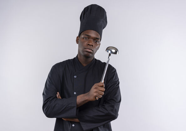 烹饪年轻自信的非洲裔美国厨师身着厨师制服 双手交叉握着勺子放在白色的空间里信心空间手臂