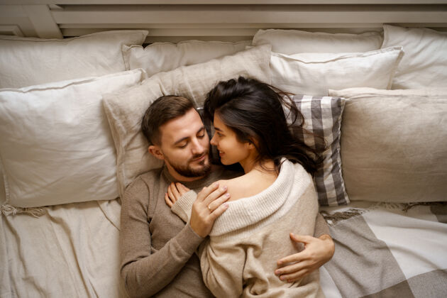 放松美丽的年轻幸福的夫妇在床上放松 微笑 拥抱男人浪漫拥抱