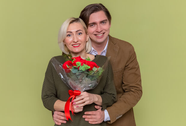 站年轻漂亮的夫妇幸福的男人与一束红玫瑰和女人年轻男人日子