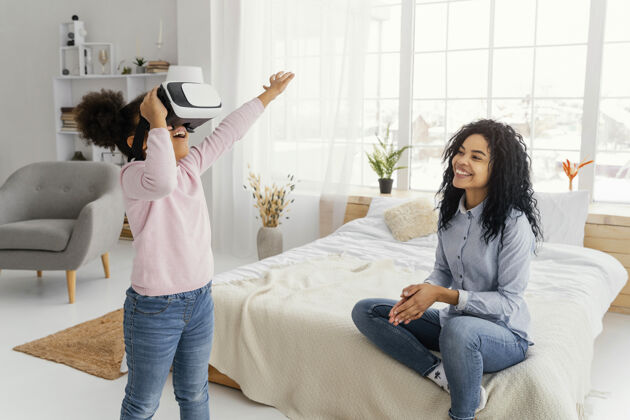 团结笑脸妈妈看女儿玩虚拟现实耳机室内娱乐娱乐