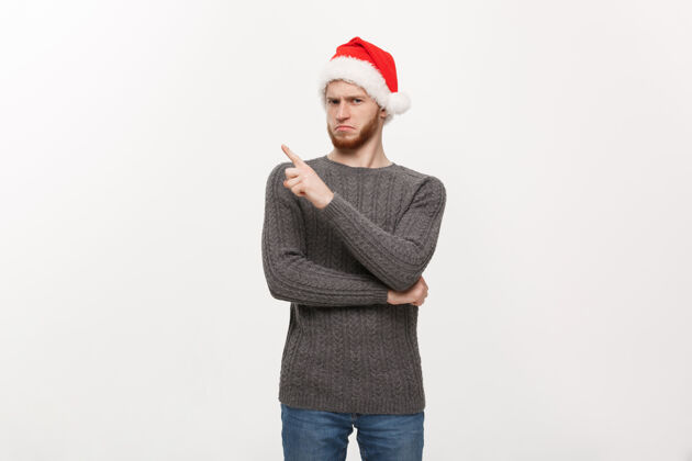 圣诞节穿毛衣的年轻胡须男喜欢边玩边指指点点指着享受红色