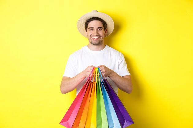 帅气快乐男人度假购物的画面 拿着纸袋 微笑着 站在黄色的背景下假期表情模特