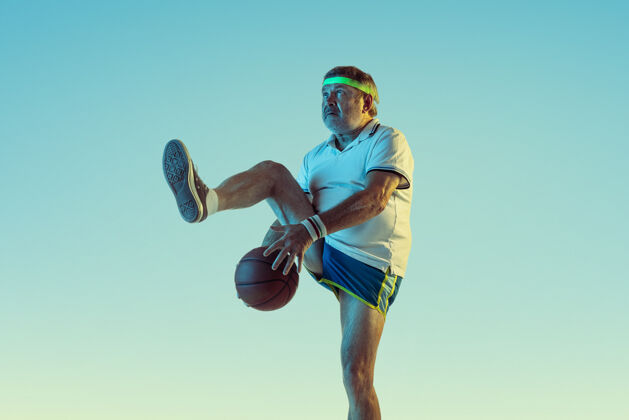 动作高级男子在霓虹灯下的斜坡墙上打篮球身材魁梧的白种人男模保持活跃 运动运动 活动 运动 幸福 健康的生活方式的概念教练比赛教练