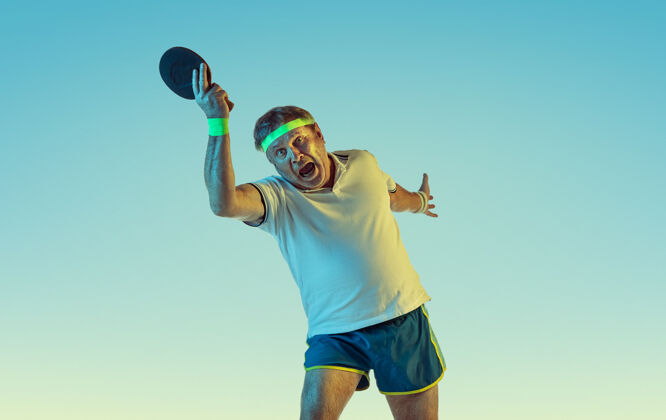 老年人资深男子在霓虹灯下的斜坡墙上打乒乓球身材魁梧的白种人男模保持活跃 运动运动 活动 运动 幸福 健康的生活方式的概念活跃动作篮球