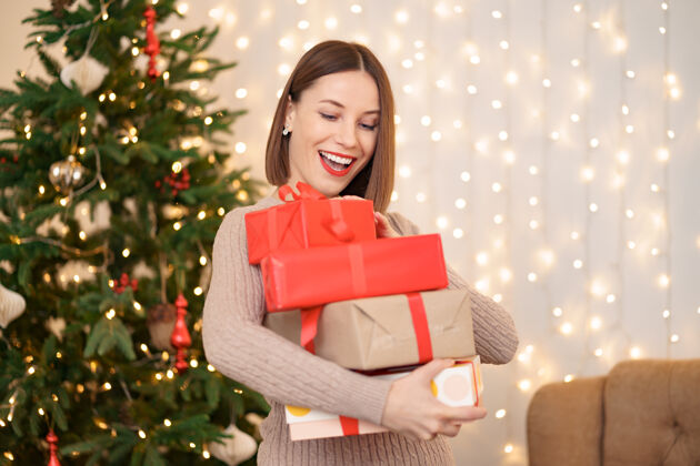 女性快乐的年轻女子拿着许多圣诞树和圣诞灯的礼物盒惊喜盒子黑发