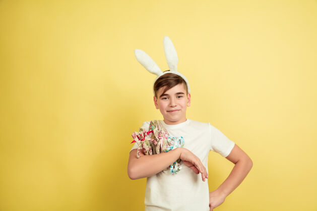 时尚男孩像复活节兔子在黄色的工作室墙上疯狂狩猎脸