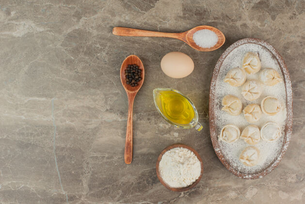 木板汤匙里有盐 胡椒 油 鸡蛋 面粉和饺子饺子食物勺子