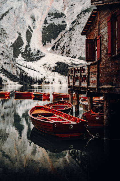 码头白天 棕色的木船在白雪覆盖的山附近的水面上自然海滨船艇