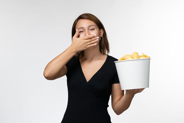 动画正面图身穿黑色衬衫的年轻女性手持薯片 在白色表面上欢笑笑电影年轻的女性