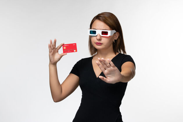 电影院正面图年轻女性手持红色银行卡戴着d墨镜在白色表面电影持有年轻的女性