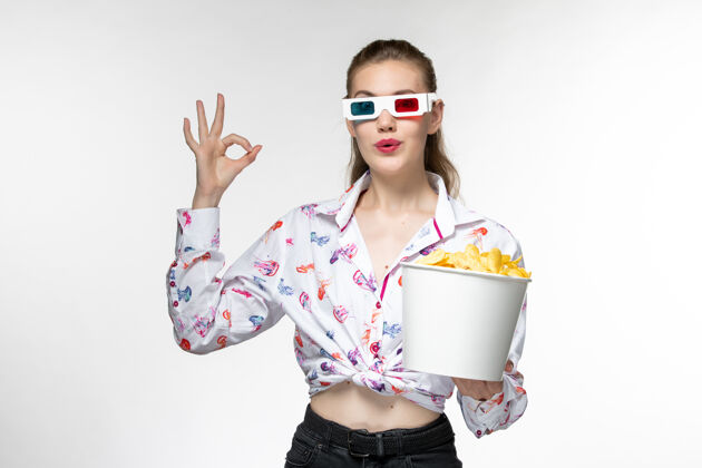 美丽正面图：白色表面上戴着d型太阳镜的年轻女性拿着土豆片的篮子电影院孤独太阳镜