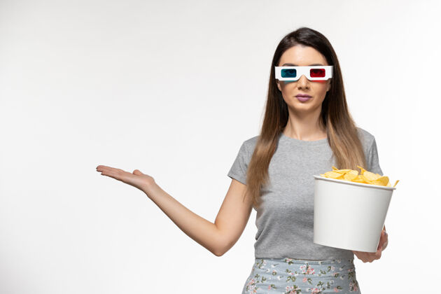 年轻的女性正面图年轻女性手持芯片 戴着d型太阳镜在浅白色表面看电影孤独电影院而