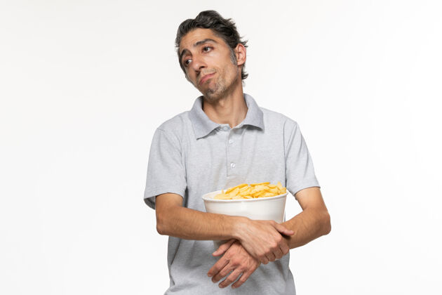 年轻男性正面图年轻男性在等待电影结束时吃薯片在白色表面青春期遥远孤独