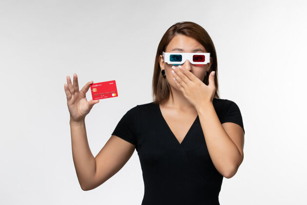 电影正面图年轻女性手持红色银行卡戴着d墨镜在白色表面电影院前面美丽