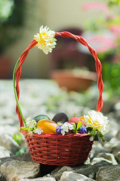 彩蛋篮子里装满了五颜六色的复活节彩蛋 石头上装饰着白花篮子摇滚花