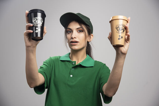 工人穿着绿色制服的送货员拿着咖啡杯摆姿势女性女人员工
