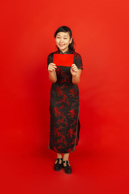 服饰年轻的亚洲女人拿着红包被隔离在红墙上祝福庆祝女性