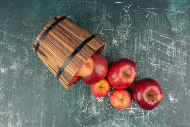 多汁红苹果从桶里掉在大理石桌上水滴苹果有机