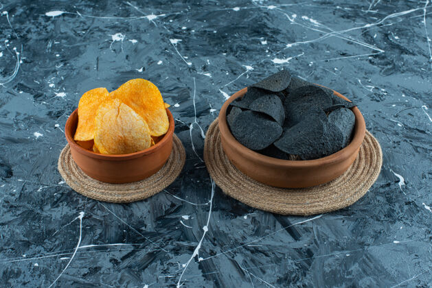 美味黑色薯片和薯片放在碗里 放在三角架上 大理石背景上薯条美味美味