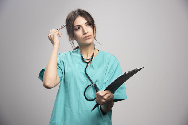 个人女医生的画像摆在灰色的剪贴板上检查健康疾病