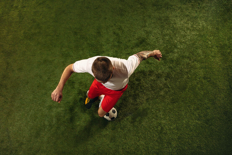 运动员白种人足球或足球运动员在草地上的绿色背景俯视图年轻男性运动模型训练 练习 踢球 进攻 接球运动概念 比赛 胜利运动员足球男