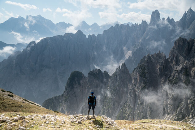 白天在意大利托布拉赫 一个人站在岩石上观看三峰自然公园的美丽照片雪美丽人