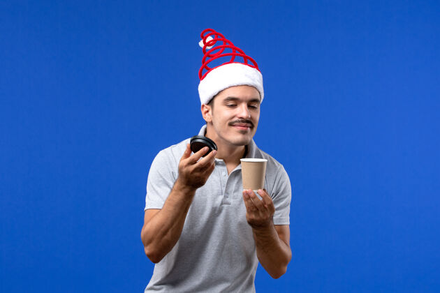 人正面图年轻男性在蓝色墙上闻咖啡新年男性节日情绪人运动圣诞节