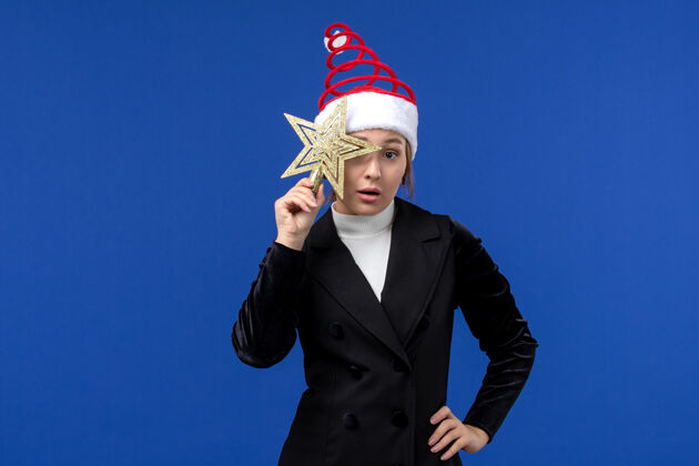 女人前视图年轻女性手持蓝色背景上的明星玩具新年妇女节日圣诞节西装举行