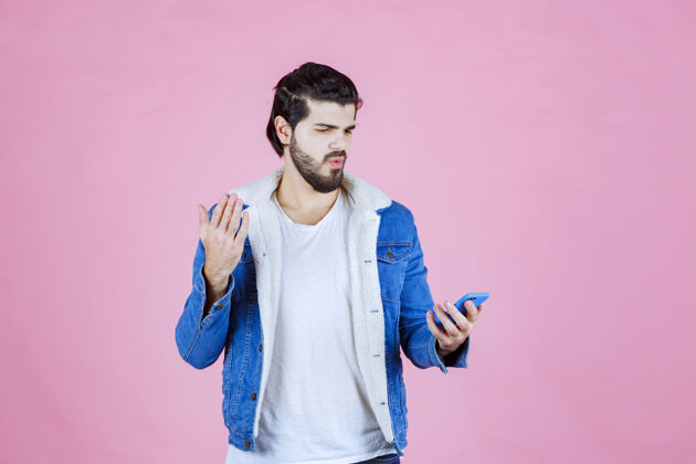压力一个穿着蓝色夹克的男人用惊奇的目光看着他的手机聪明员工兴奋