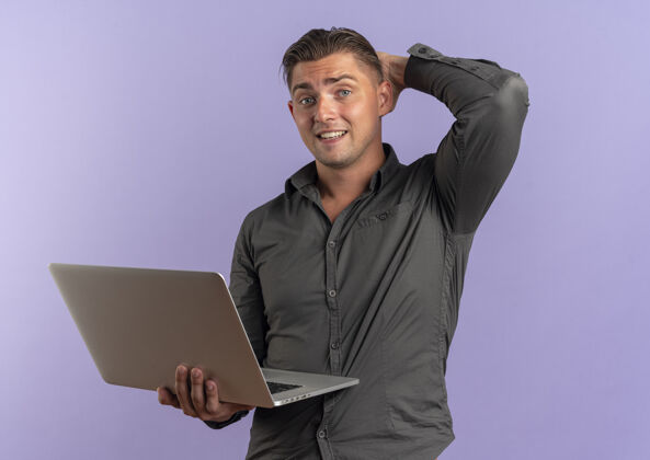 复制年轻微笑的金发帅哥拿着笔记本电脑 把手放在脖子后面孤立的紫色空间和复印空间男人紫罗兰空间