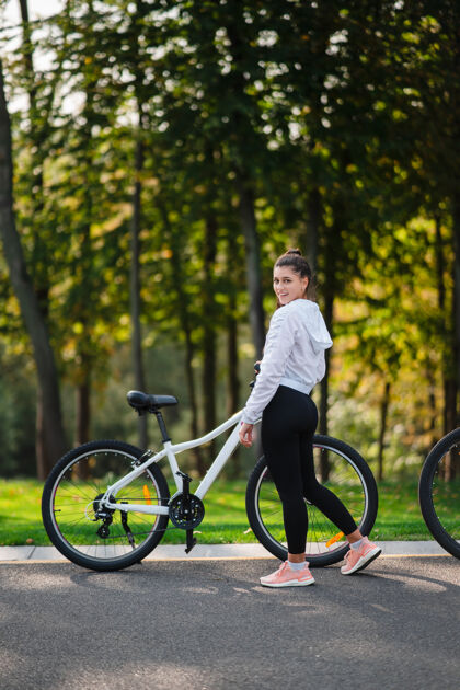 肖像美丽的女孩在白色自行车前摆姿势在大自然中行走健康的生活方式公园女孩年轻