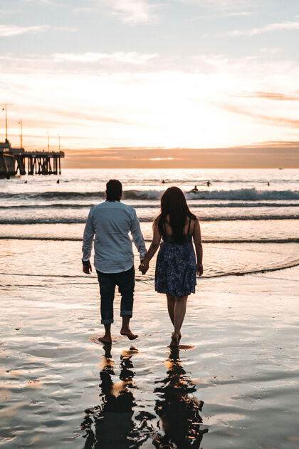 海滩白天在海边散步的情侣手牵手海洋情侣一起