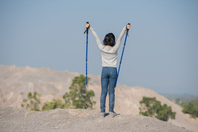 女孩快乐的亚洲小女孩在山上徒步旅行站在一个多岩石的山顶山脊和电线杆上眺望风景岩石耐力活动