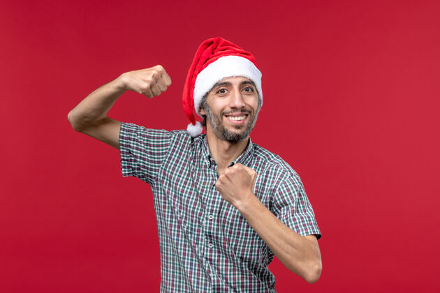 帽子正面图红墙上戴新年帽的年轻人红色新年假期男圣诞节娱乐商人