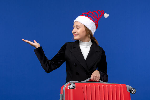 年轻女性正面图年轻女子提着红包在蓝色书桌上旅行度假度假的女人成功工人人