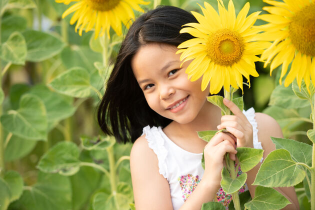 黄色快乐的亚洲小女孩在阳光下 在盛开的向日葵中嬉戏户外欢呼春天
