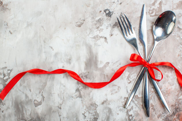 食品顶视图银色餐具与红色蝴蝶结在灯光表面笔厨房羽毛笔