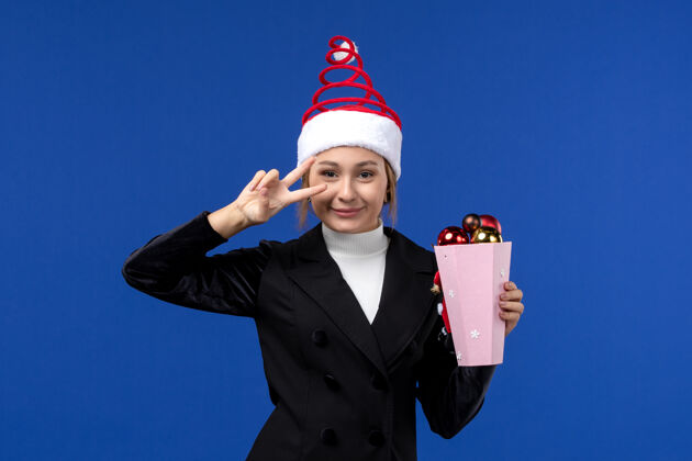 微笑正面图年轻女性微笑着蓝色墙上的圣诞树玩具新年假期情感色彩观点成功颜色