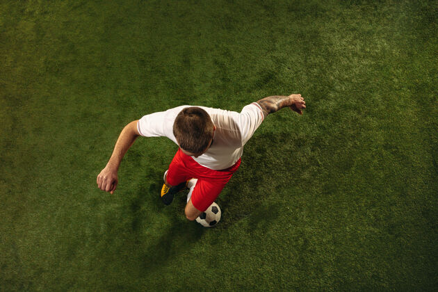 运动员白种人足球或足球运动员在草地上的绿色背景俯视图年轻男性运动模型训练 练习 踢球 进攻 接球运动概念 比赛 胜利运动员足球男