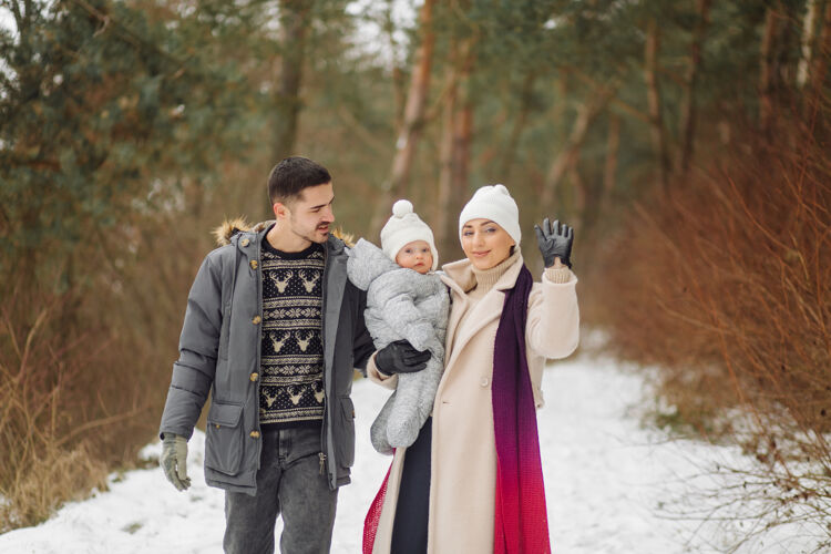 女性在一个阳光明媚的日子里 一家人在雪中散步 在冬季公园里玩得开心 互相拥抱 面带微笑孩子微笑关系