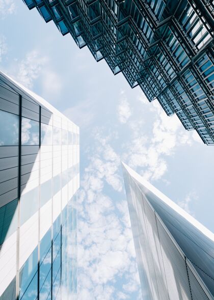 街道低角度垂直拍摄的现代建筑与天空中多云的蓝色窗户云城市景观