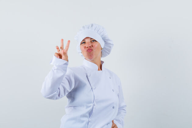 女士女厨师穿着白色制服展示v字标志 看起来很自信模特表情自信