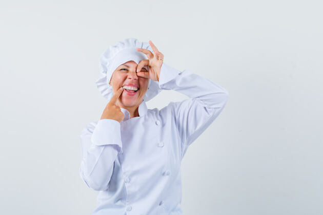 女士一位身穿白色制服的女厨师在眼睛上显示“ok”标志 看上去很乐观优雅制服乐观