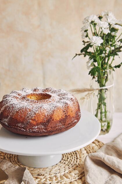 传统美丽的镜头美味的环蛋糕放在一个白色的盘子和一个白色的花靠近它蛋糕面粉垂直